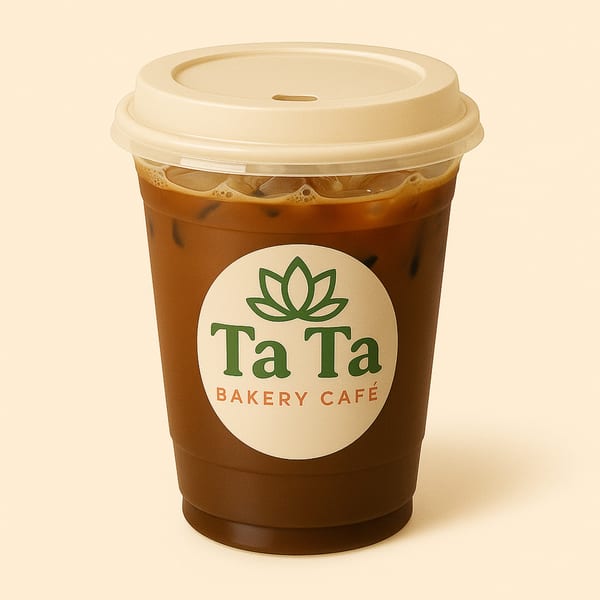 Iced coffee in a clear plastic cup with a light brown lid and the TaTa Bakery Café logo.